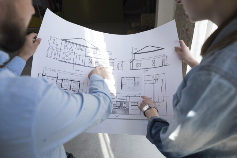 colleagues-holding-blueprint-discussing-project-office